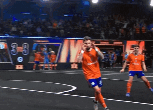 a soccer player wearing an orange shirt with the number 3 on the front