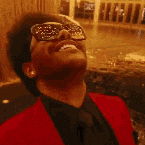 a close up of a man wearing sunglasses and laughing with his mouth open .