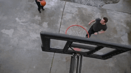 a woman playing basketball in a driveway with a hoop in the background