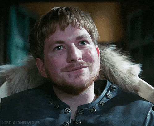 a man with a beard and a fur collar is smiling and looking up