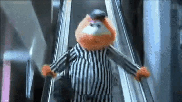 a stuffed animal is riding an escalator wearing a striped shirt