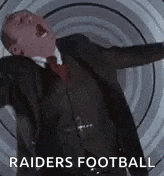 a man in a suit and tie is screaming while standing in front of a spiral .