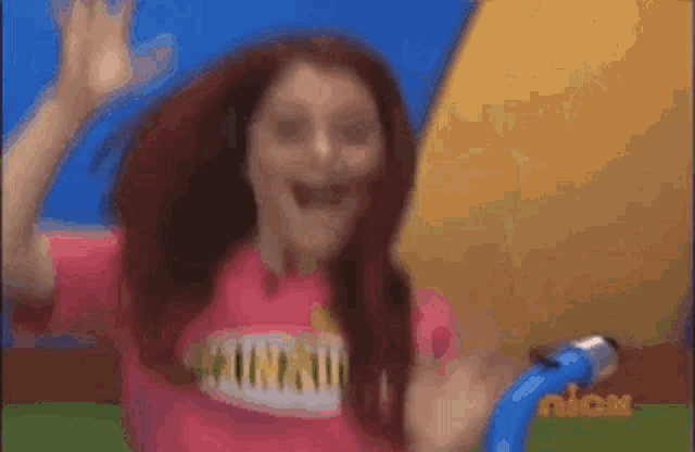 a girl with red hair is wearing a pink shirt that says ariana grande on it .
