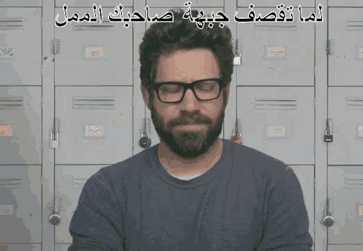 a man wearing glasses and a beard is standing in front of a wall of lockers