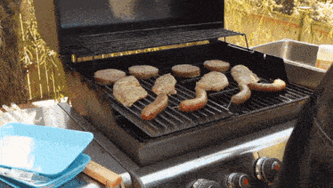 a grill with hamburgers and sausages on it with a bottle of cleaner in the background