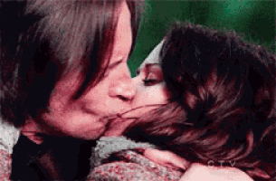 a man and a woman are kissing with a green background behind them .
