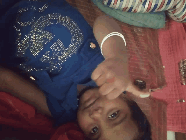 a little girl wearing a blue shirt with the letter g on it is laying on a bed