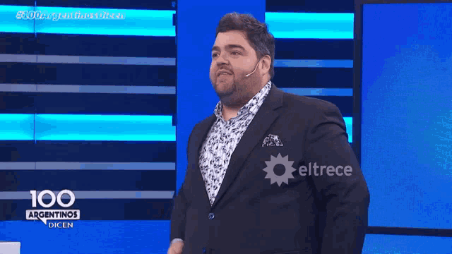 a man in a suit is standing in front of a screen that says 100 argentinas dicen