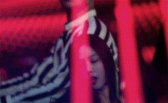 a man and a woman are standing next to each other in a dark room behind red bars .