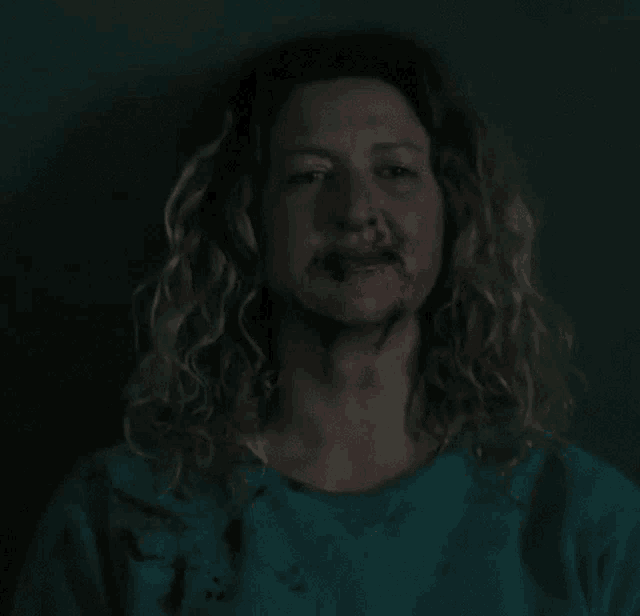 a woman with blood on her face is wearing a green shirt