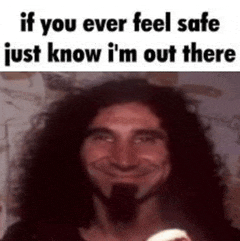 a man with long curly hair and a beard is smiling while holding a baby .