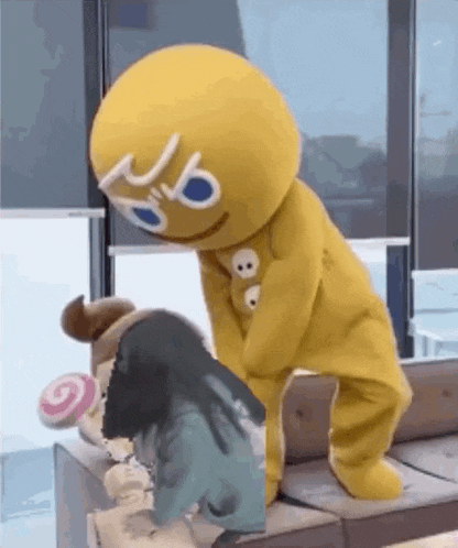 a gingerbread man mascot is standing next to a woman .