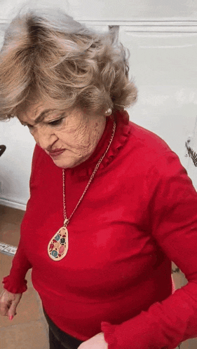 a woman wearing a red sweater and a gold necklace