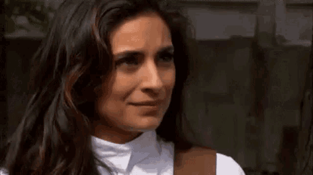 a woman with long dark hair is making a sad face .