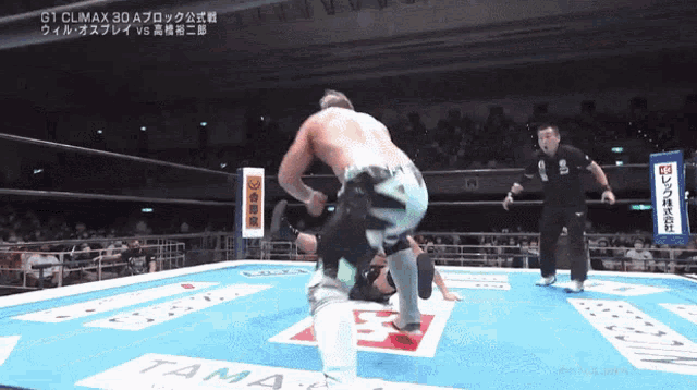 a man in a wrestling ring with a sign that says tama on the floor
