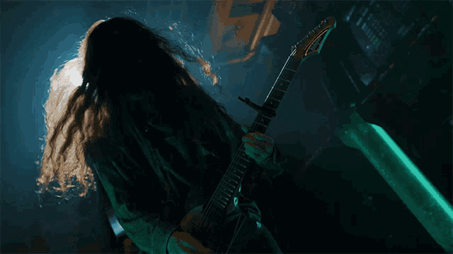 a man with long hair is playing a guitar that says ibanez