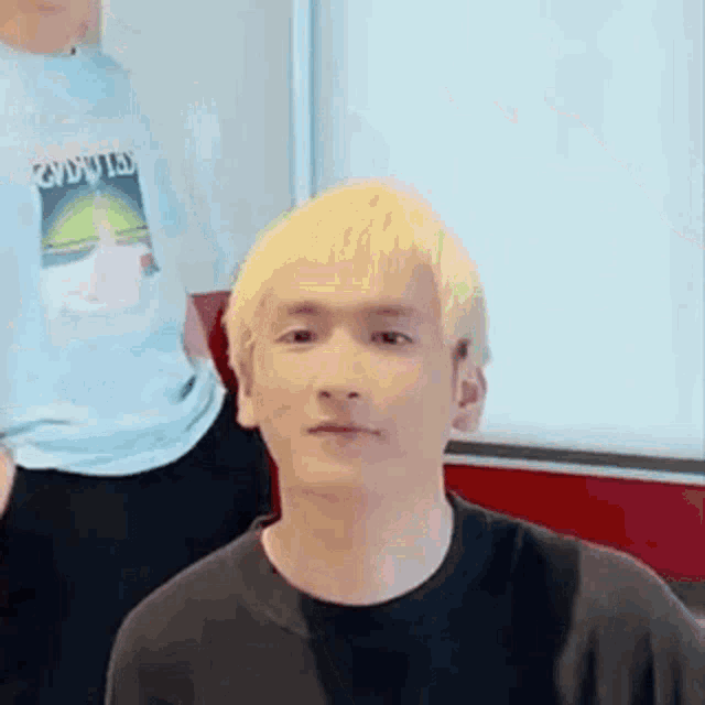 a young man with blonde hair is wearing a black t-shirt .