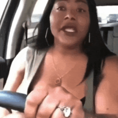 a woman is sitting in the driver 's seat of a car talking .