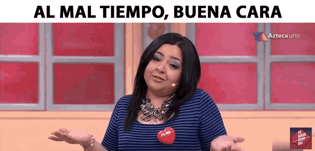 a woman wearing a blue striped shirt with a red heart on her chest says al mal tiempo buena cara in spanish
