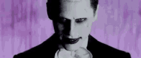 the joker is wearing a tuxedo and bow tie and is smiling .