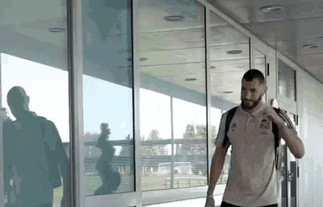 a man is walking down a hallway with a backpack and talking on a cell phone .