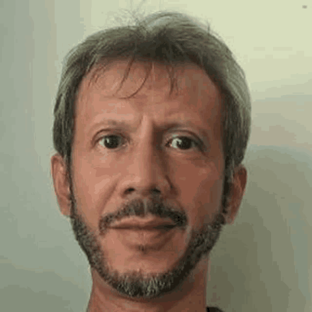 a man with a beard is looking at the camera .