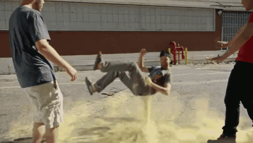 a man in a blue shirt is doing a trick on a yellow powder