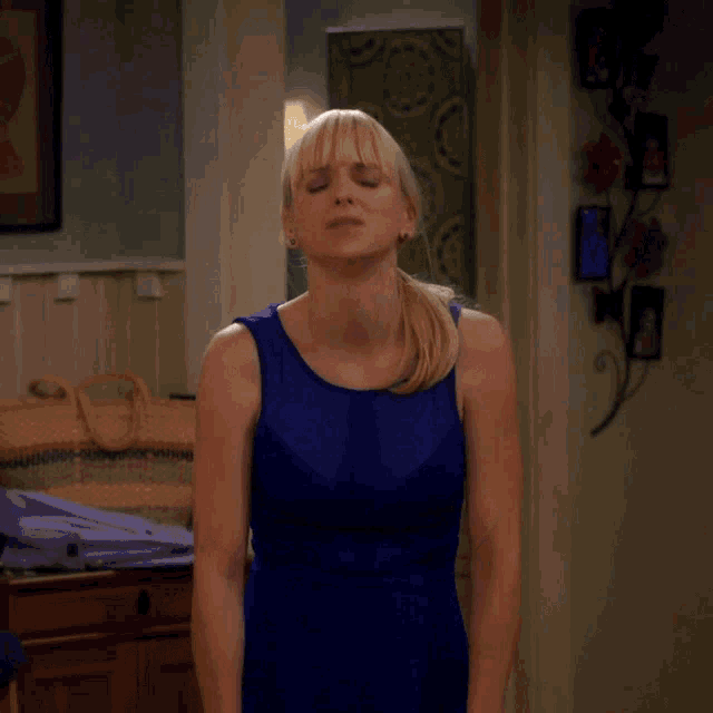 a woman in a blue dress stands in front of a sign that reads dammit