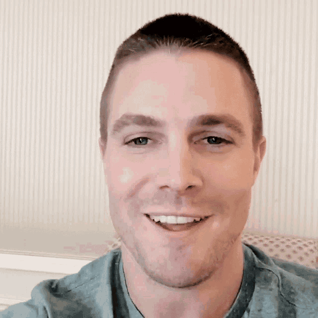 a close up of a man 's face with a striped wall behind him
