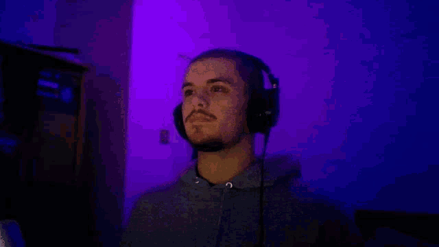 a man wearing headphones and sunglasses is sitting in a dark room