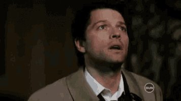 a man in a trench coat and tie is looking up .