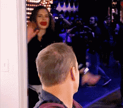 a man and a woman are standing in a doorway and the woman is making a funny face .
