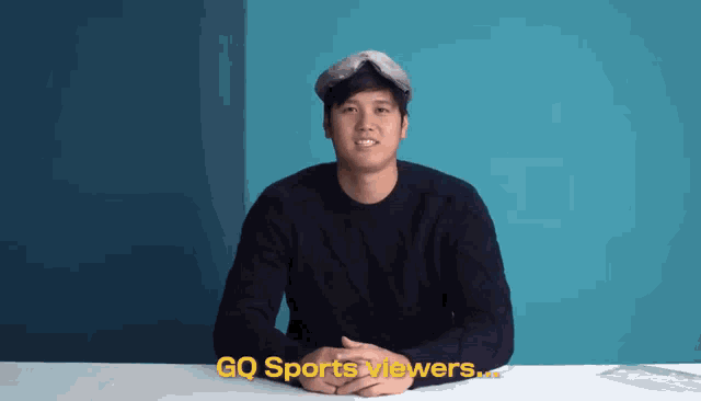 a man is sitting at a table with gq sports viewers written on the bottom
