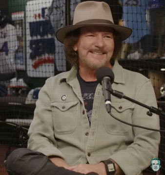 a man wearing a hat is sitting in front of a microphone with a watch on his wrist