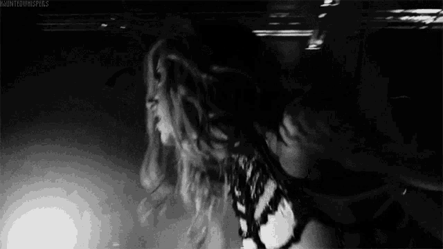 a black and white photo of a woman with long hair dancing .