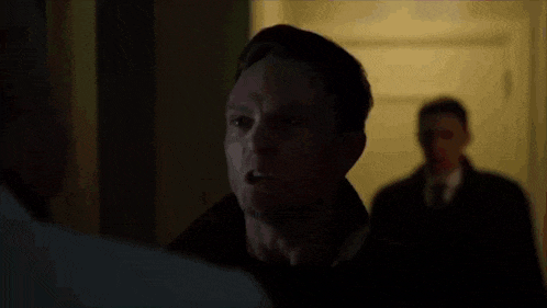 a man in a black hat is fighting another man in a white shirt in a room .