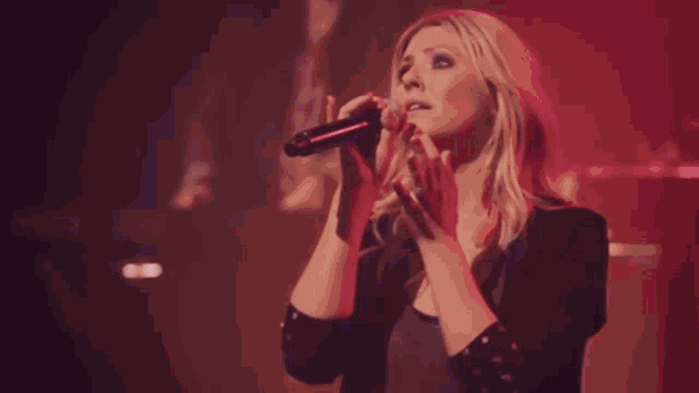 a man is singing into a microphone in a dark room .