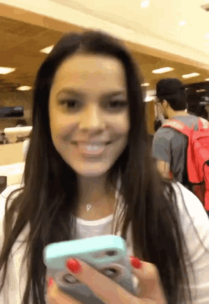 a woman with red nails is smiling and holding a phone
