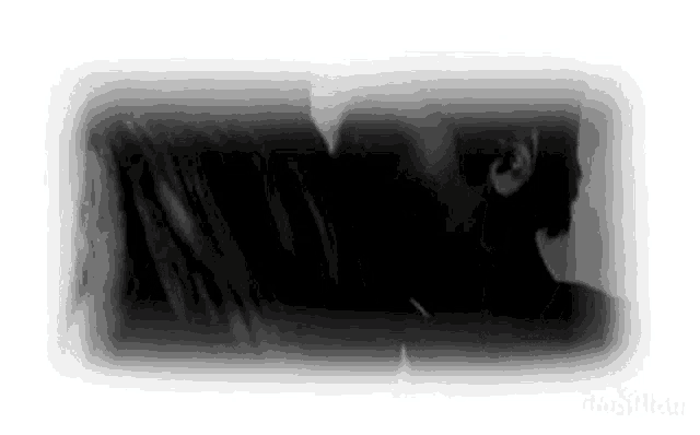 a black and white photo of a man and woman kissing each other .