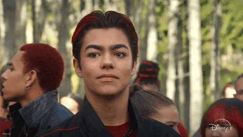 a young man with red hair is standing in front of a crowd of people with disney + written on the bottom