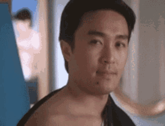 a man without a shirt is looking at the camera .