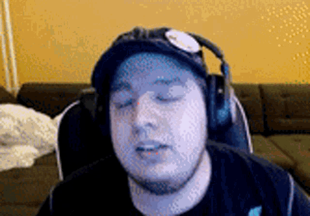 a man wearing headphones and a hat is sitting in front of a computer screen .