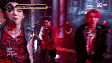 a group of men are standing on a stage with a mnet logo in the background .
