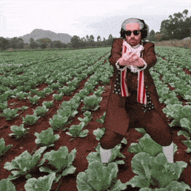 a man is standing in a field of lettuce wearing headphones and an american flag scarf