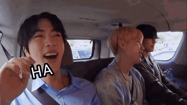 a group of young men are sitting in the back seat of a car and one of them has the word ha on his face .