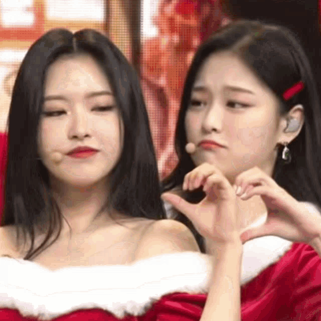 two young women are making a heart shape with their hands .
