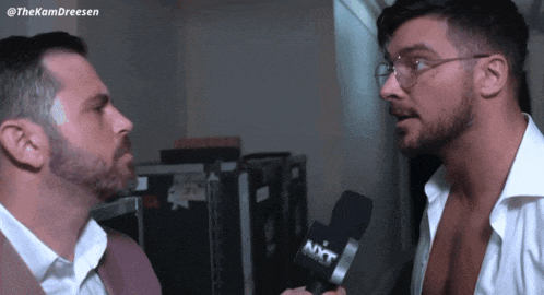two men are talking to each other with a microphone that says nxt on it