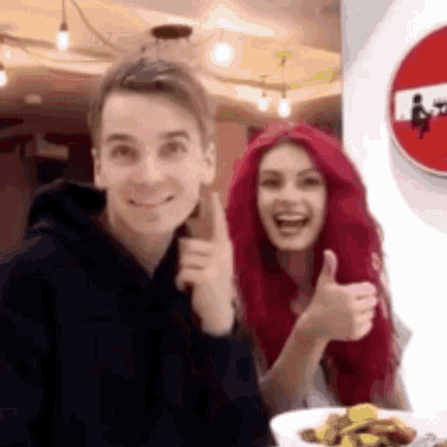 a man and a woman are giving a thumbs up