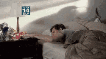a man is sleeping in a bed with a tv 14 dlv logo on the wall behind him