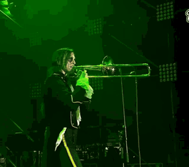 a man is playing a trombone in front of a green light